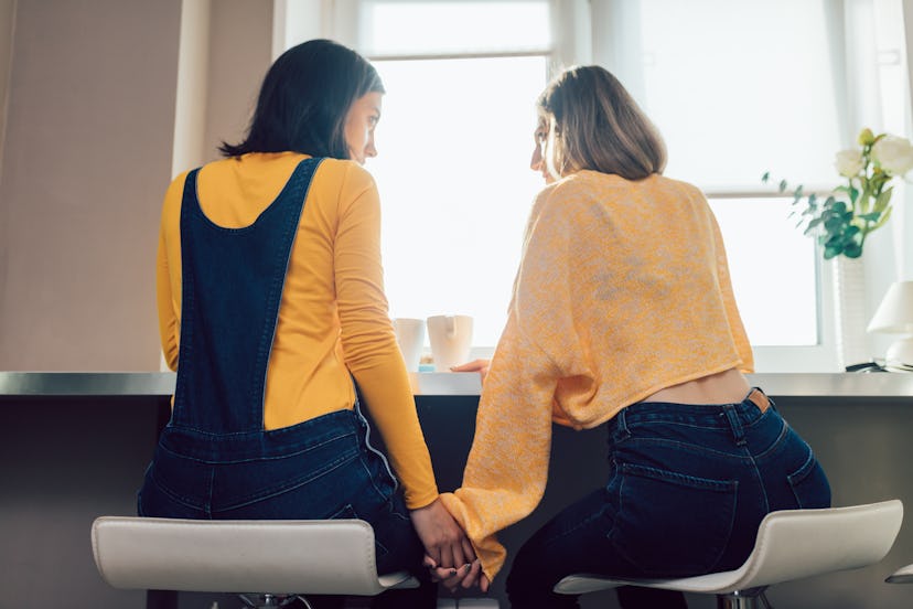 two lesbians having a snack in the morning. back view photo. relationship, love concept. serious con...