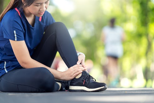 Young asian woman suffering ankle injury. Runner girl is injured by sprain ankle while running or ex...