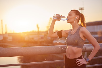 Young woman drinking water after running
