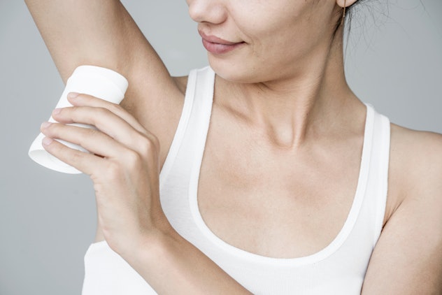 Woman applying deodorant on her armpit