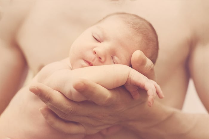 Naked tiny newborn baby in daddy's hands, monochrome