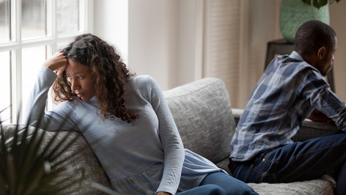 Depressed mixed race couple sit separate on couch having relationships problems, stressed upset blac...