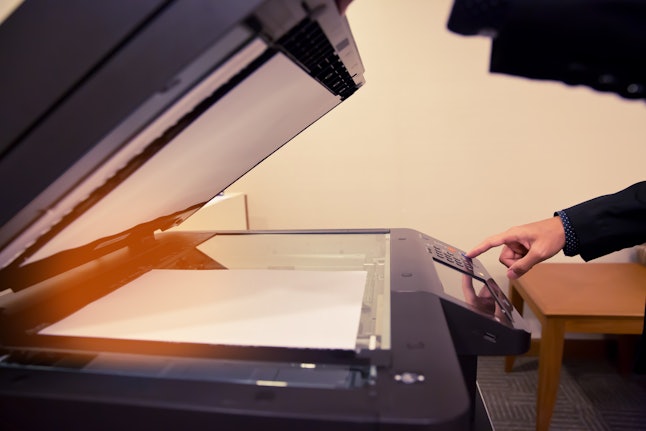 Close-up hand Businessmen press Start Button are using photocopiers in the room.