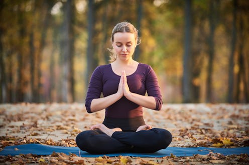 Beautiful young woman meditates in yoga asana Padmasana - Lotus pose on the wooden deck in the autum...