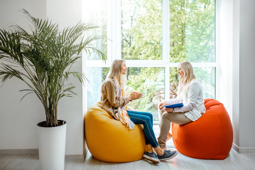 Young woman with senior female psychologist or mental coach sitting on the comfortable chairs during...