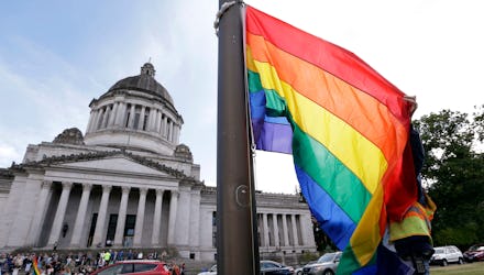 A state worker unfurls a rainbow flag in front of the Washington state Capitol to prepare it to be r...