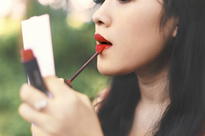 woman makeup lips with mirror on park