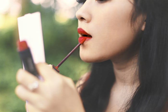 woman makeup lips with mirror on park