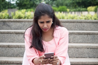 Worried young woman text messaging on mobile phone
