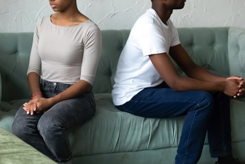 Crop close up of african American husband and wife sit separately back to back on couch avoid talkin...