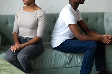 Crop close up of african American husband and wife sit separately back to back on couch avoid talkin...