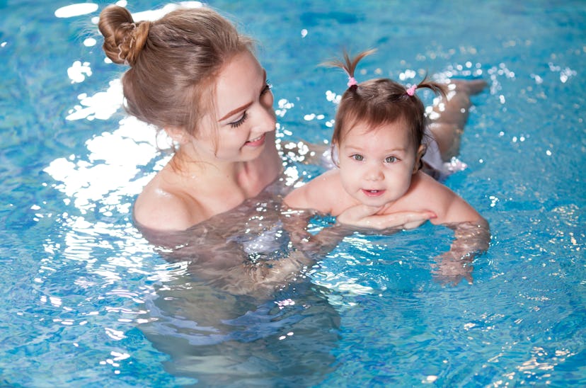 young mother bathes the baby in the pool