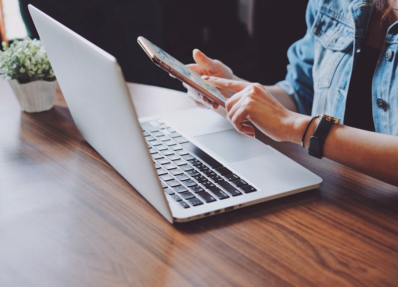 Young hipster woman using smartphone and laptop in office or home