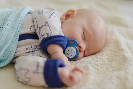 newborn with dummy sleeping on the bed