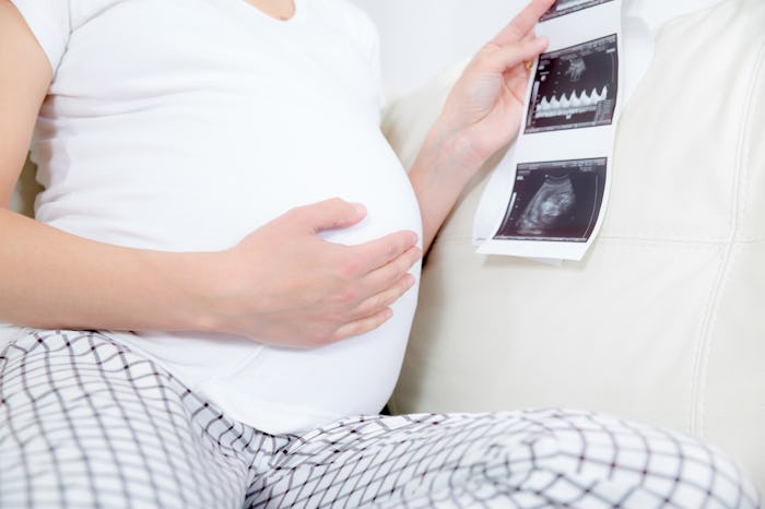 Pregnant woman hands holding ultrasound photo