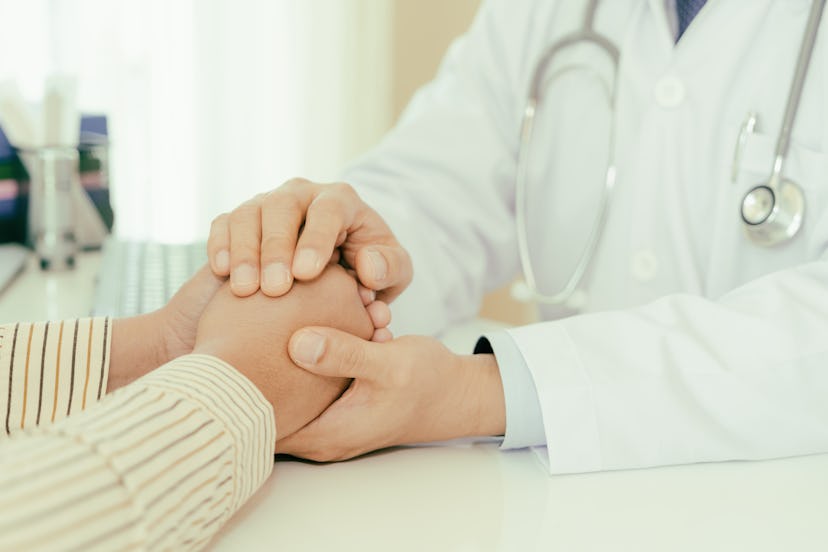 Friendly man doctor hands holding patient hand sitting at the desk for encouragement, empathy, cheer...