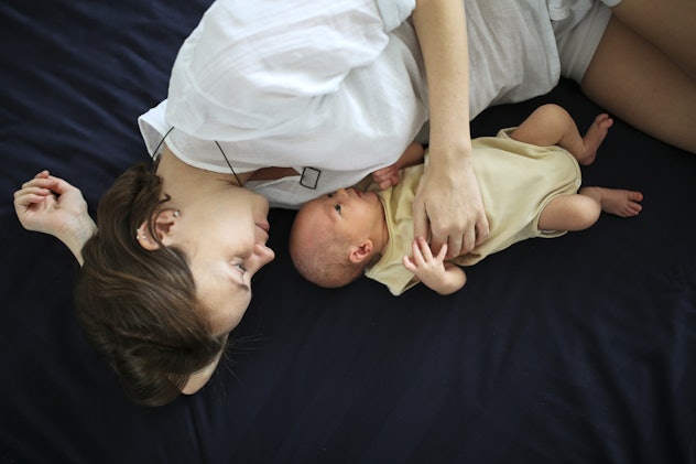 newborn with mom on a dark sheet, baby and mother on the bed, concept of motherhood