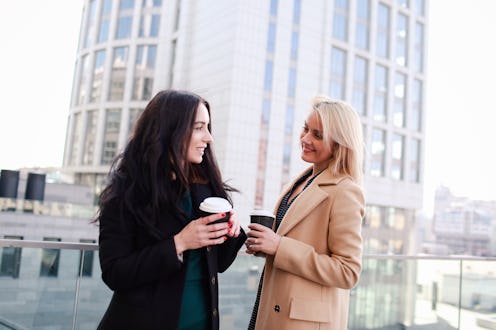 two women walk in the city, drink coffee and enjoy the rest