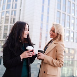 two women walk in the city, drink coffee and enjoy the rest