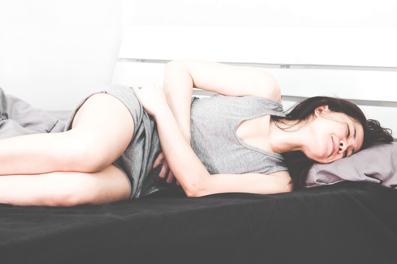 woman wearing gray clothes in the bed,
She is not comfortable,stomachache,tummyache