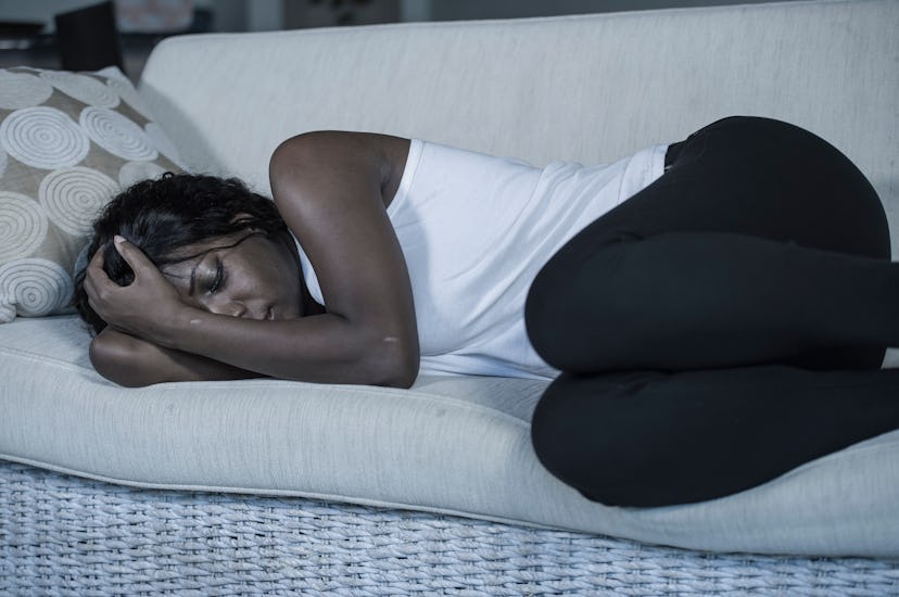 young attractive and sad black African American woman lying depressed at home sofa couch feeling anx...