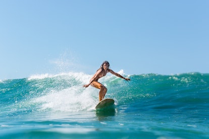 Beautiful young brunette girl in a bikini swimsuit ride wave. Sporty surfer woman surfing in Mauriti...