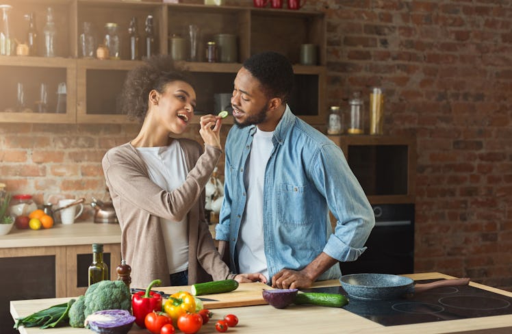 Happy african-american couple preparing dinner in loft kitchen at home. Family cooking healthy food