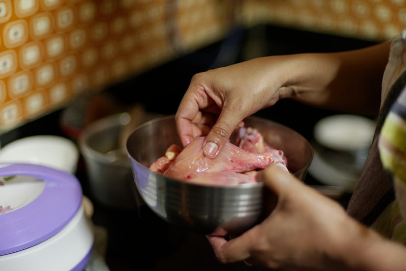 Raw chicken meat is being washed before cooking in an Indian kitchen. Indian lifestyle