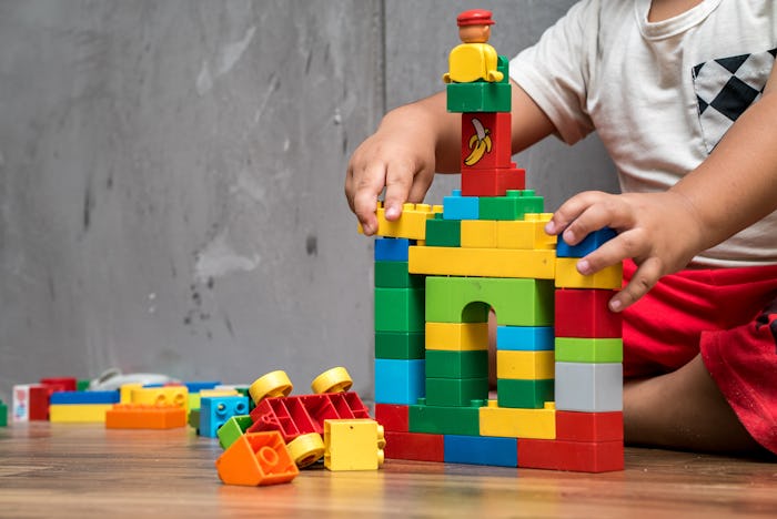 Asian kid boy building house from plastic blocks