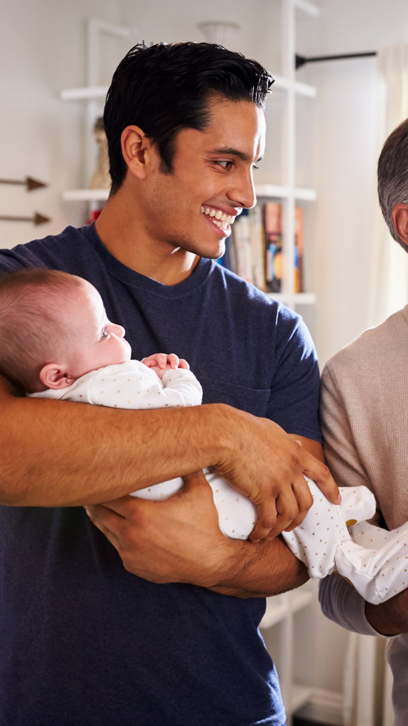 Young Hispanic man and his senior father holding his two baby boys at home