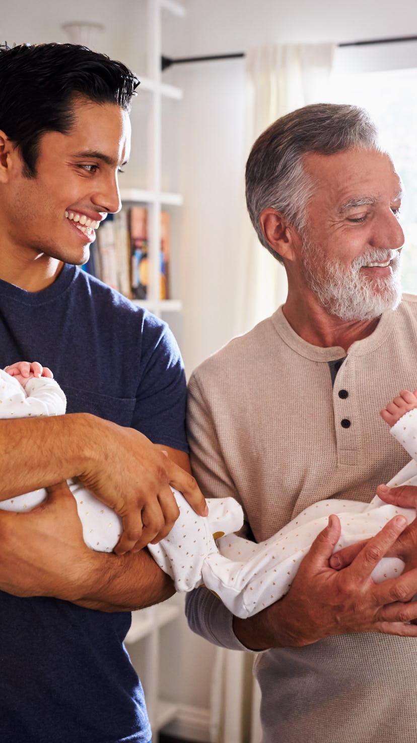 Young Hispanic man and his senior father holding his two baby boys at home