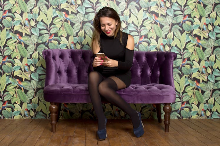 Smiling woman prepared to party  with phone on the purple sofa