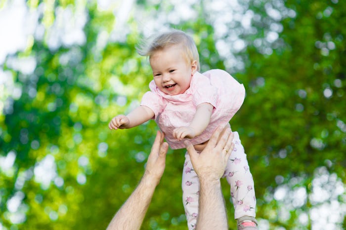 Happy family. Father throws up baby in the air in nature
