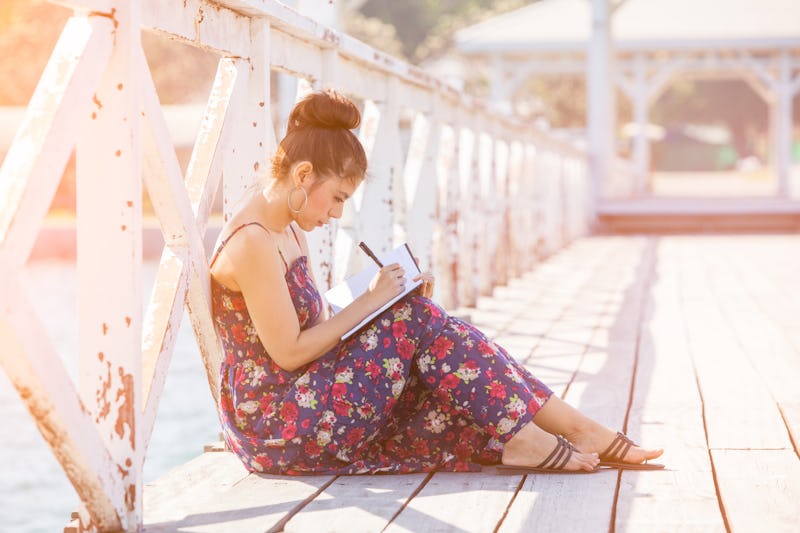 Woman writing by pen in notepad at sunny summer