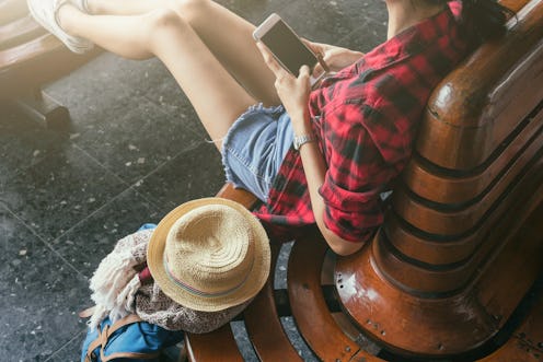 Woman traveler holding smart phone on wood chair with travel accessories,travel accessories concept ...