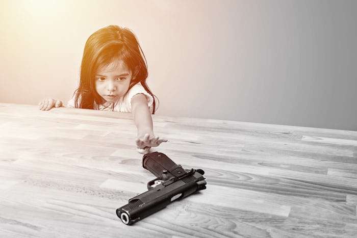 safety and accident in home concept. children try to play parent's gun on table. monotone color