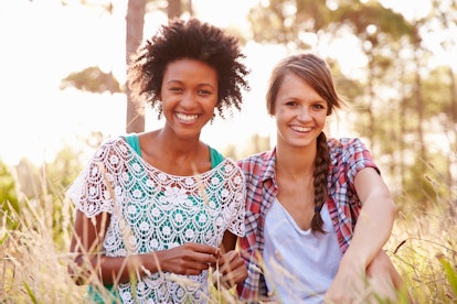 Portrait Of Two Smiling Young Women Sitting In Countryside