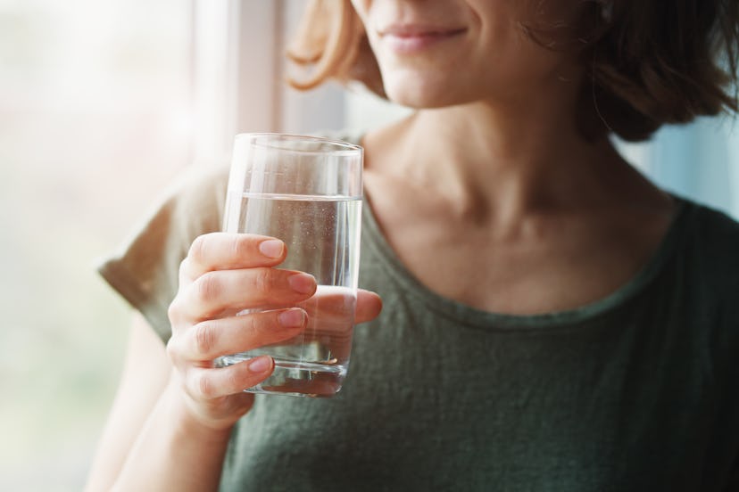 Young woman holding a glass of water, one of the best natural remedies for constipation