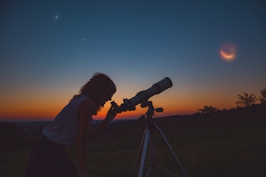 Girl looking at lunar eclipse through a telescope. My astronomy work.