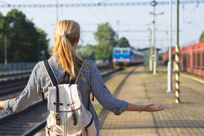 I am late! Woman standing on railroad station and looking to leaving train. Traveler is worried, bec...