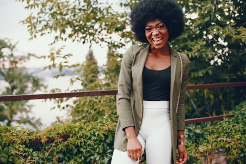 Fashionable girl in a summer city. Black lady in a green jacket