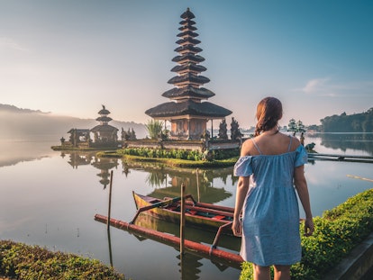 Young woman near Pura Ulun Danu Bratan temple near Beratan lake in Bali island, Indonesia at sunrise...