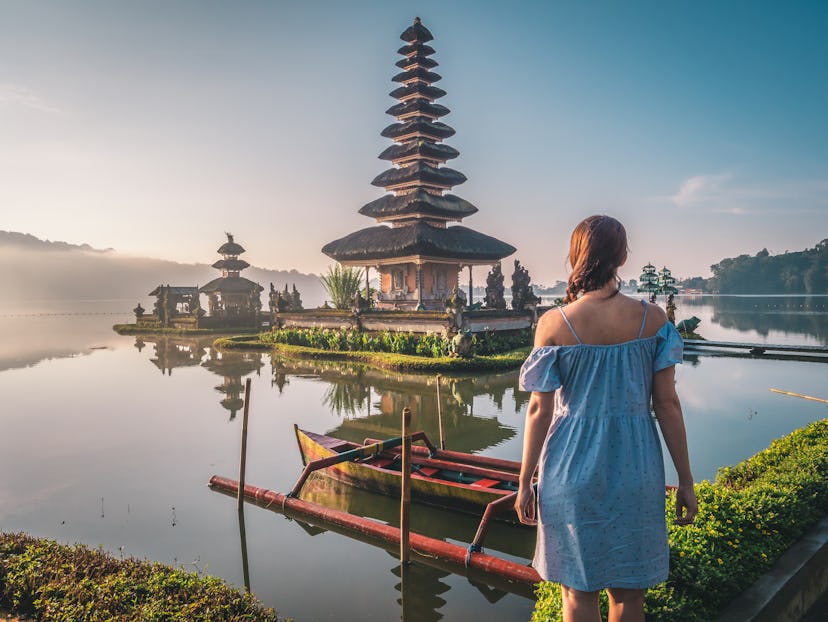 Young woman near Pura Ulun Danu Bratan temple near Beratan lake in Bali island, Indonesia at sunrise...