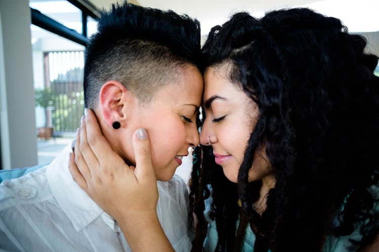 Happy lesbian couple embracing each other and smiling in living room