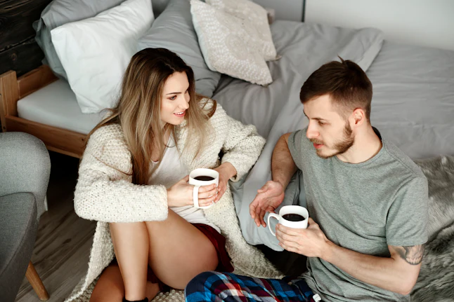 Couple with coffee sitting on floor and talking