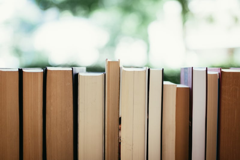 Stack of books, blurry background: Charity book flea market, outdoors. Text space.