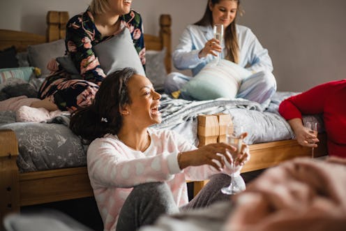 Small group of female friends relaxing and talking while enjoying a girls night in. They are sitting...