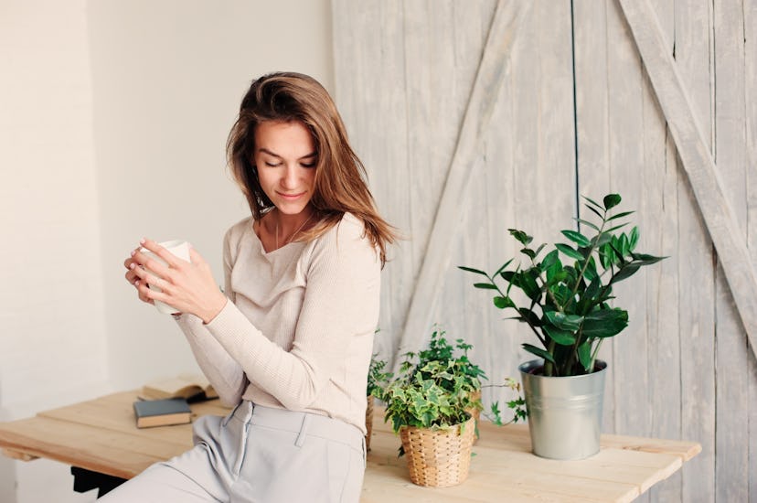 beautiful young feminine woman relaxing at home in lazy weekend morning with cup of coffee, wearing ...