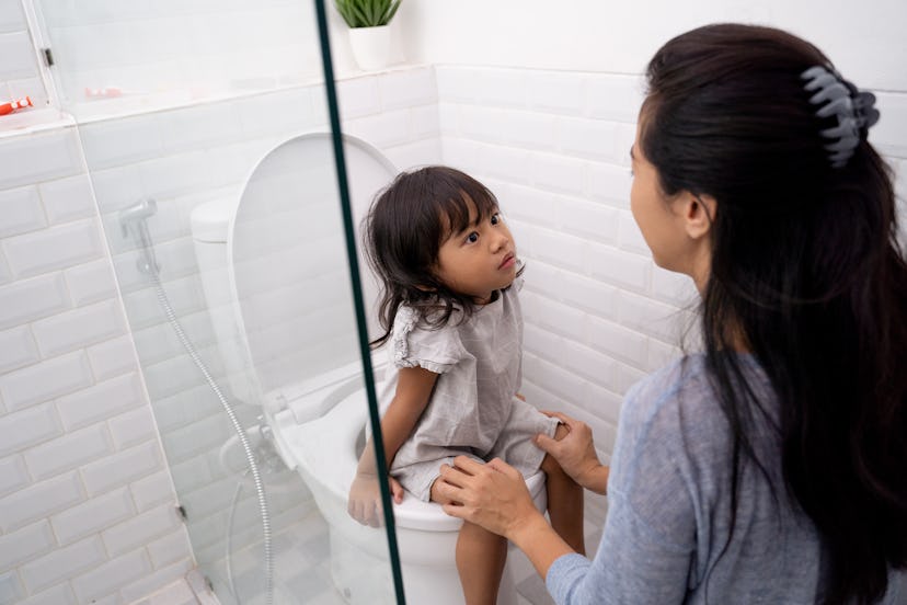 mother help her kid to use toilet. toilet training for toddler with mom