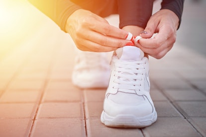 Woman get ready for run. Female hands tying shoelaces on sport sneakers
